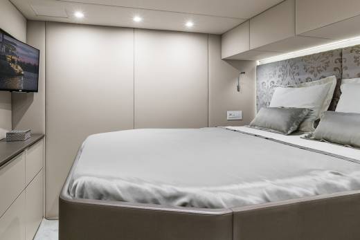 Luxurious bedding and a mounted television create a serene and modern retreat aboard this elegant yacht.