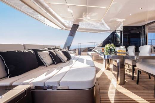 Relax on the plush outdoor seating of this luxurious yacht while enjoying a refreshing drink at the sleek dining table.