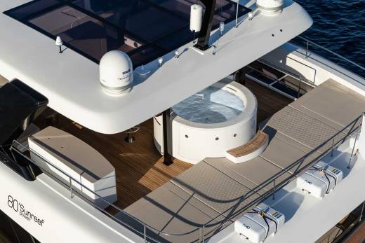 A luxurious yacht features a circular jacuzzi and spacious sundeck with life rafts and a Cypriot flag.