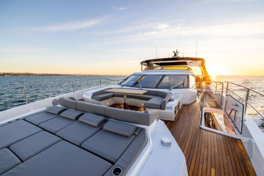Golden hour illuminates the luxurious deck of a yacht as it cruises across the calm sea.