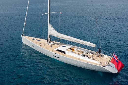 A sleek white yacht glides through the deep blue ocean, its sails furled and flags flying.