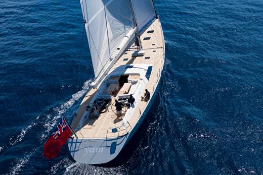 A majestic sailboat glides through the deep blue ocean under a clear sky.