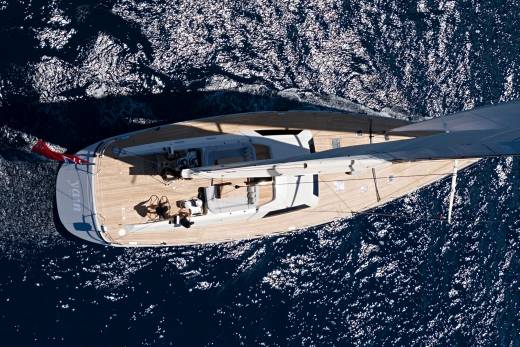A sleek yacht glides through the sparkling blue ocean under a clear sky.