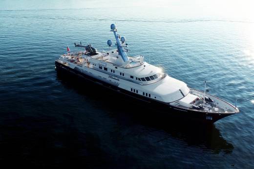 A large, luxurious yacht glides across the calm, blue waters, surrounded by the serene ocean backdrop.