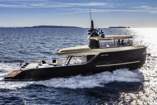 A sleek, modern yacht cruises through sparkling blue waters under a bright sky.