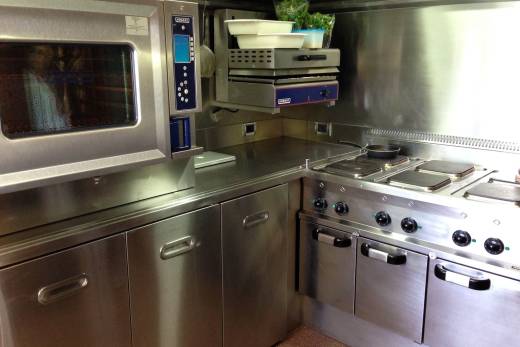 A professional stainless steel kitchen features a convection oven, induction cooktop, and ample storage.