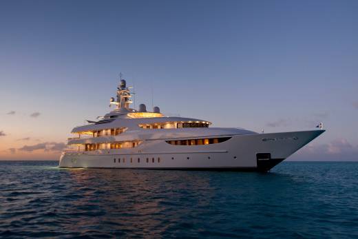 The luxurious yacht Oasis glides serenely on calm waters under a twilight sky.
