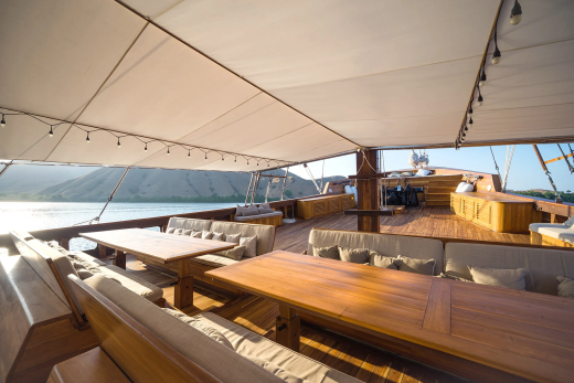 Relax on the spacious deck of this traditional wooden boat, complete with comfortable seating and dining areas.
