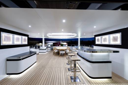 Elegant bar seating and a circular dining table create a sophisticated atmosphere on this yacht's deck.