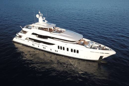 A luxurious white yacht glides serenely across the deep blue ocean under a clear sky.