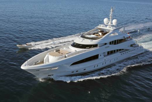 A sleek white yacht cruises through the deep blue ocean, leaving a foamy wake behind it.