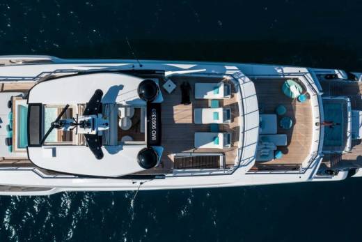 A luxurious yacht with a helipad and swimming pool glides across the deep blue ocean.