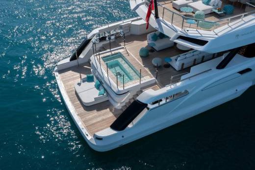 A luxurious yacht with a sparkling pool and plush seating areas floats on the shimmering blue ocean.