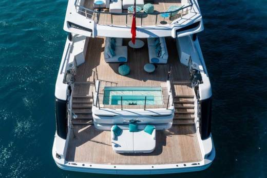 A luxurious yacht with a pool and lounge areas floats serenely on the deep blue ocean.
