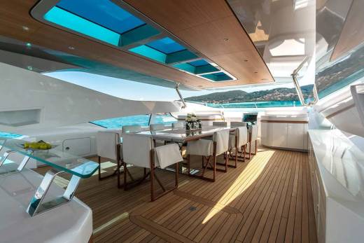 Luxurious yacht dining area with a table set for a meal, overlooking a stunning coastal landscape.