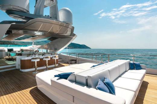 Luxurious white sofas and a sleek bar await guests on the sun-drenched deck of this opulent yacht.