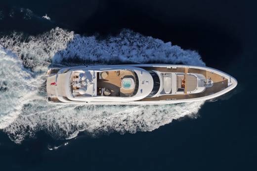 A luxurious yacht glides through the deep blue ocean, leaving a trail of white foam in its wake.