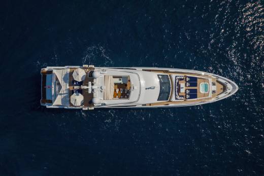 A luxurious yacht glides through the deep blue sea, offering a serene escape with its elegant decks and inviting jacuzzi.