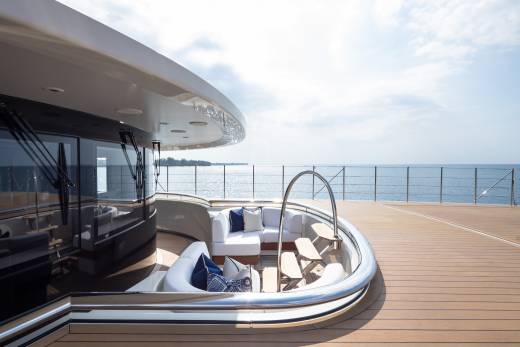 Luxurious white seating and wooden decks invite relaxation on this sleek yacht overlooking the tranquil ocean.