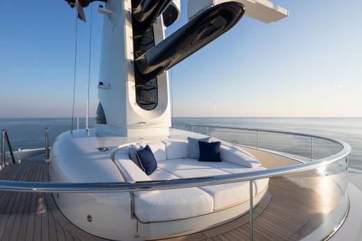 A luxurious yacht deck offers a serene spot to relax with plush white cushions and a stunning ocean view.