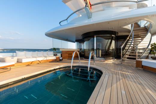 A luxurious yacht deck features a serene swimming pool and comfortable seating, perfect for a relaxing day at sea.