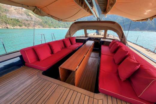 Luxurious red cushions and polished wood create an inviting seating area on this elegant yacht, ready for guests to enjoy the turquoise waters.