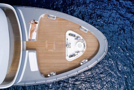 A woman in a bikini sunbathes on the deck of a luxurious yacht as it glides through the deep blue ocean.