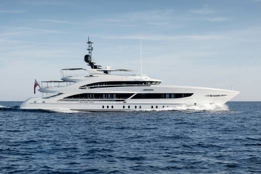 The sleek white yacht Arkadia glides through the deep blue ocean under a clear sky.