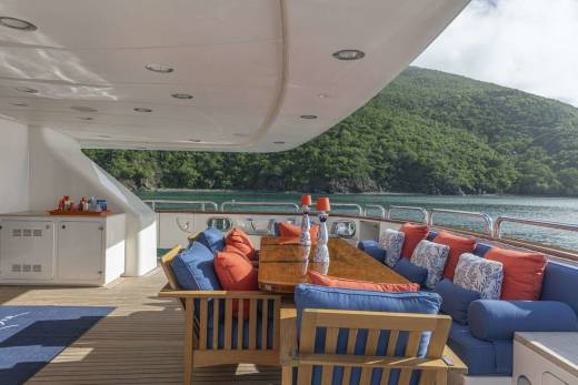 Relax on the spacious deck of this luxury yacht, surrounded by lush green hills and the sparkling blue sea.