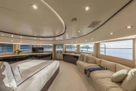 Luxurious yacht interiors offer stunning ocean views from a plush sectional sofa and a comfortable king-sized bed.