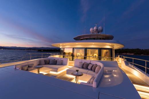 Luxurious outdoor seating on a yacht offers a breathtaking view of the sunset over the water.