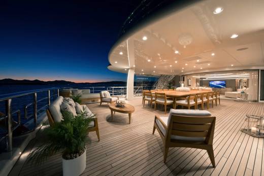 A luxurious yacht deck at dusk offers a serene setting for al fresco dining and relaxation with a stunning ocean view.
