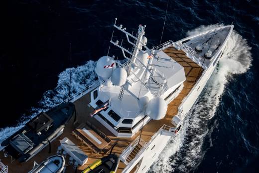 A sleek white yacht cuts through the deep blue ocean, leaving a frothy wake in its path.