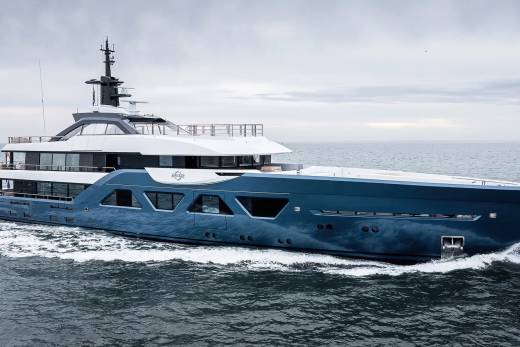 A large, modern yacht with a sleek, angular design is sailing across the open ocean under a cloudy sky.