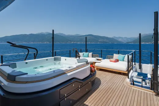 Relax in the bubbling hot tub on the deck of this luxurious yacht, with stunning mountain views in the distance.
