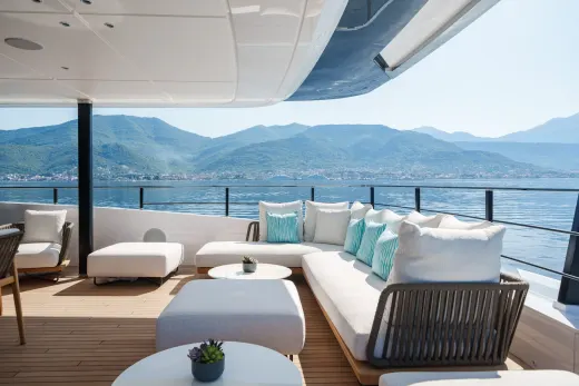 Relax on the luxurious deck of a yacht with stunning views of verdant mountains meeting the serene blue sea.
