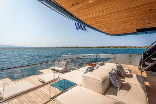 Relax on the luxurious deck of a yacht, surrounded by the tranquil blue waters and distant islands under a clear sky.
