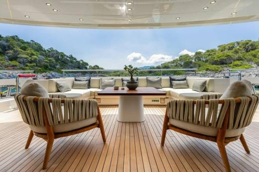 Relax on the luxurious deck of a yacht with comfortable seating and stunning views of a lush, green coastline.