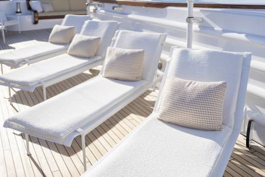 Sun-drenched lounge chairs await relaxation on the teak deck of a luxurious yacht.