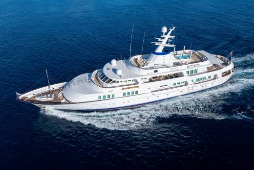 The elegant yacht Lady Beatrice cruises through the deep blue ocean, leaving a white wake in its path.