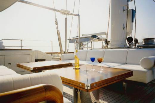 Two wine glasses and a bottle of white wine await guests on a yacht's polished wooden deck.