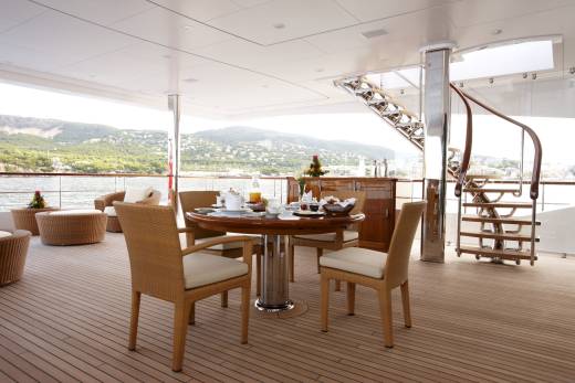 Enjoy a delightful breakfast on the deck of this luxurious yacht, overlooking a picturesque coastal landscape.