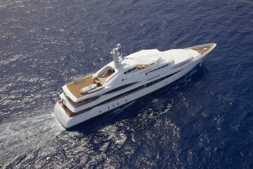 A luxurious white yacht glides through the deep blue ocean, leaving a frothy wake behind it.