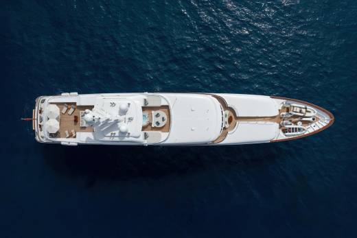A luxurious superyacht glides through the deep blue sea, its decks adorned with sun loungers and tenders.
