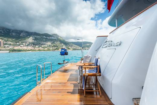 Relax on the teak deck of a luxury yacht with stunning views of the Mediterranean coast.
