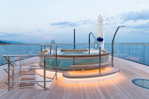 Relax in the illuminated jacuzzi on the deck of this luxurious yacht as the sun sets over the tranquil sea.