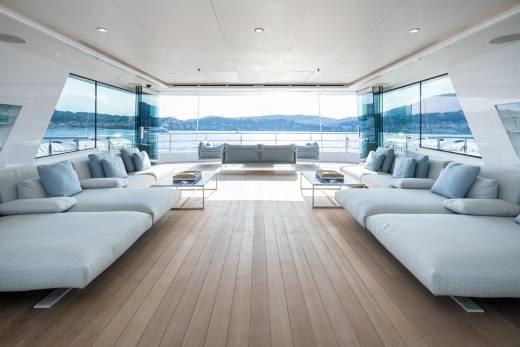 Luxurious yacht interiors open onto a sun-drenched deck with stunning ocean views and comfortable seating.