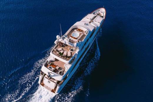 A luxurious white yacht glides through the deep blue ocean, leaving a trail of white foam in its wake.