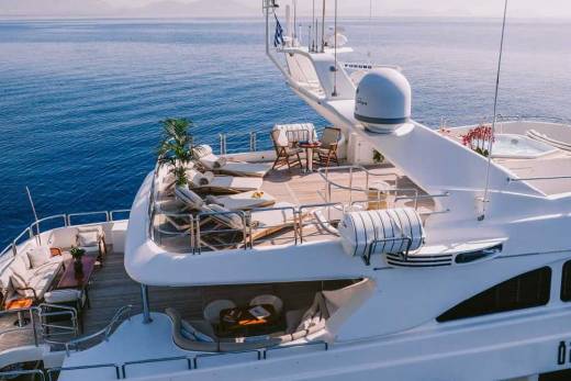 Luxurious yacht decks offer ample space for relaxation with comfortable seating, sun loungers, and a soothing hot tub against a backdrop of the serene blue sea.
