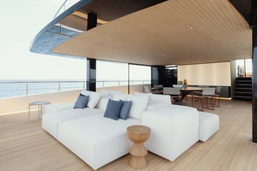 Relax on the spacious deck of this luxurious yacht, featuring plush white seating and a stunning ocean view.